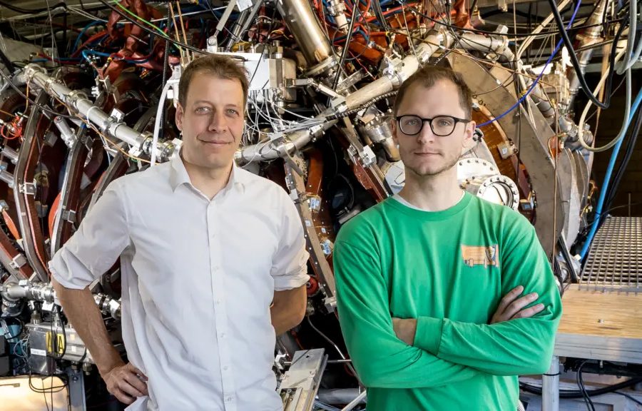 Prof. Benedikt Geiger and student Michael Gerrard standing in front of HSX experiment