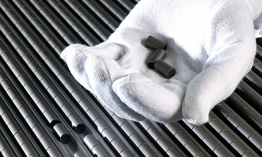 Fresh nuclear fuel pellets in a gloved hand